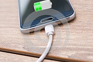 Mobile phone and battery charger cable on office desk photo