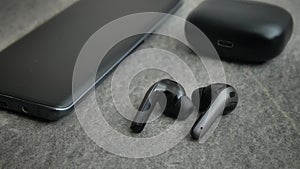 Mobile phone with blank screen and headphones on surface. Wireless headphones, mobile phone black, top view. copy space