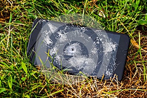 Mobile phone with a broken touch screen and a hole from the bullet. Shooting during hostilities_