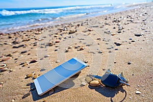 Mobile phone and car keys on beach sand