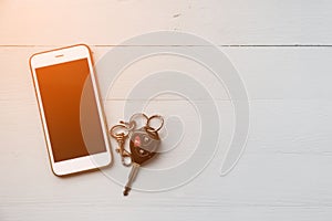 Mobile phone and car remote keys on wooden background