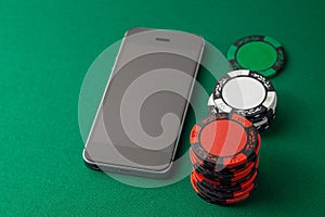 Mobile phone casino online. Mobile phone and chips on green gaming table. Gambling addiction in cracking games. Poker online