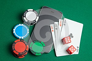 Mobile phone casino online. Mobile phone and game cards with chips and dice on a green gaming table. Gambling addiction