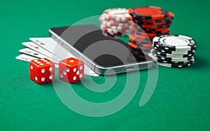 Mobile phone casino online. Mobile phone and game cards with chips and dice on a green gaming table. Gambling addiction