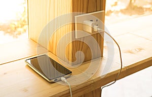 Mobile phone charger plugged on wooden pole