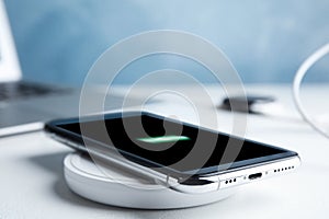 Mobile phone charging with wireless pad on stone table, closeup. Space for text