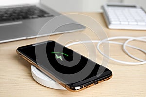 Mobile phone charging with wireless pad on table, closeup