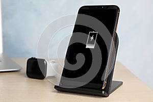 Mobile phone charging with wireless pad on wooden table
