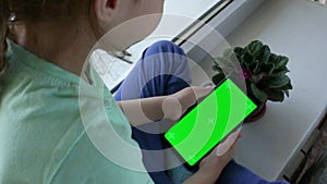 Mobile phone in children's hands. Chromed green screen. View over the shoulder. Viewing Internet content as a child. video.