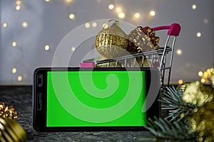 Mobile phone with chromakey on the background of Christmas decorations. Bokeh. Chromakey. Space for text