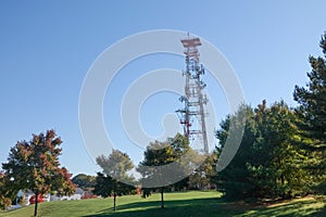 Mobile phone communication antenna tower with the blue sky near a residential community