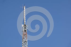 Mobile phone communication antenna tower with satellite dish on blue sky background, Telecommunication tower
