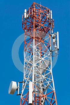 Mobile phone communication antenna tower with satellite dish on blue sky background