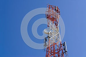 Mobile phone communication antenna tower with satellite dish on blue sky background