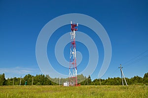 Mobile phone communication radio tv tower, mast, cell microwave antennas and transmitter against the blue sky and trees