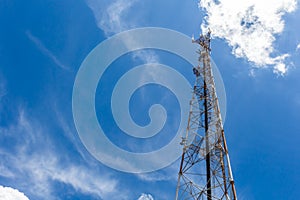 Mobile phone communication repeater antenna tower, with blue sky and white clouds