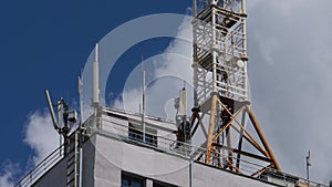 Mobile phone communication tower on building roof on blue sky background