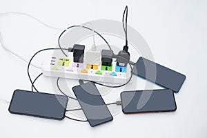 Mobile Phone connected to charging hubs on electric socket.