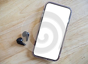 Mobile phone with empty screen and earphones on white surface. Wireless earphones