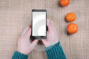 Mobile phone in female hands and fruits on a background, oranges and grapefruits