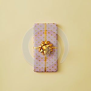 The mobile phone is gift-wrapped with a gold ribbon and a bow