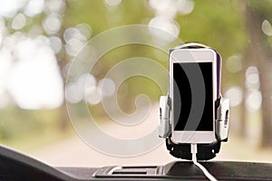 Mobile phone with GPS card in the car. A white smartphone on a stand in the car is used for navigation.