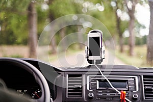 Mobile phone with GPS card in the car. A white smartphone on a stand in the car is used for navigation.