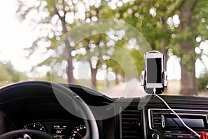 Mobile phone with GPS card in the car. A white smartphone on a stand in the car is used for navigation.