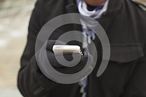 Mobile phone in hands with glowes, cold weather