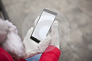 Mobile phone in hands with glowes, cold weather