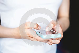 Mobile phone in the hands of a woman. The girl is typing a text message on her smartphone. Cell phone. Dependence on gadgets.