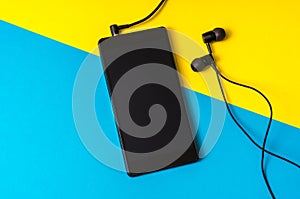 Mobile phone with headphones on colorful background