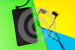 Mobile phone with headphones on colorful background