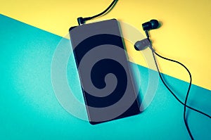 Mobile phone with headphones on colorful background