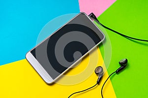 Mobile phone with headphones isolated on colorful background