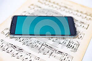 Mobile phone lies on a sheet of music notes