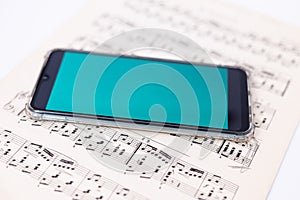 Mobile phone lies on a sheet of music notes