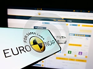 Mobile phone with logo of car safety programme Euro NCAP on screen in front of website.