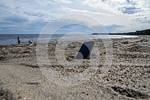 Mobile phone lying on the beach in the sand. weatherproof phones, lost phone concept, data loss photo