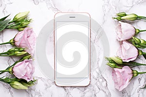 Mobile phone mock up with pink flowers on marble background