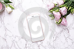 Mobile phone mock up with pink flowers on marble background