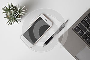 Mobile phone mockup, top view of White office desk table with mockup blank screen smartphone and computer laptop. Flat lay top