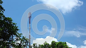 Mobile phone network coms tower with cloudscape and treetops