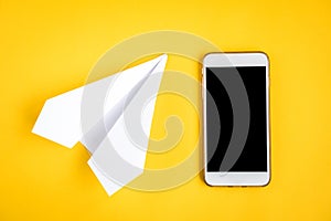 Mobile phone and paper airplane on yellow background. Travel concept. Speed Internet concept
