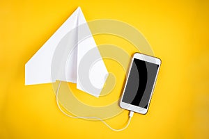 Mobile phone and paper airplane on yellow background. Travel concept. Speed Internet concept
