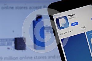 Mobile phone with PayPal logo on screen close up with website on laptop. Blurred background with Pay Pal and free space for text.