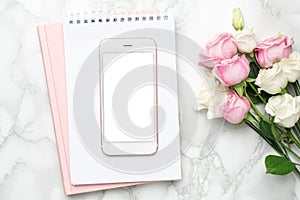 Mobile phone with pink and white roses flowers on marble background.Minimalistic composition for the holidays,valentines