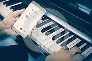 Mobile phone is recording the sound of man playing piano