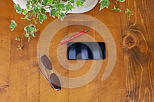 Mobile phone, red pen and dark glasses on rustic wooden background