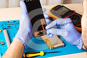 mobile phone repairing. The master remotes the mobile phone using tools on a special mat. flat lay, top view